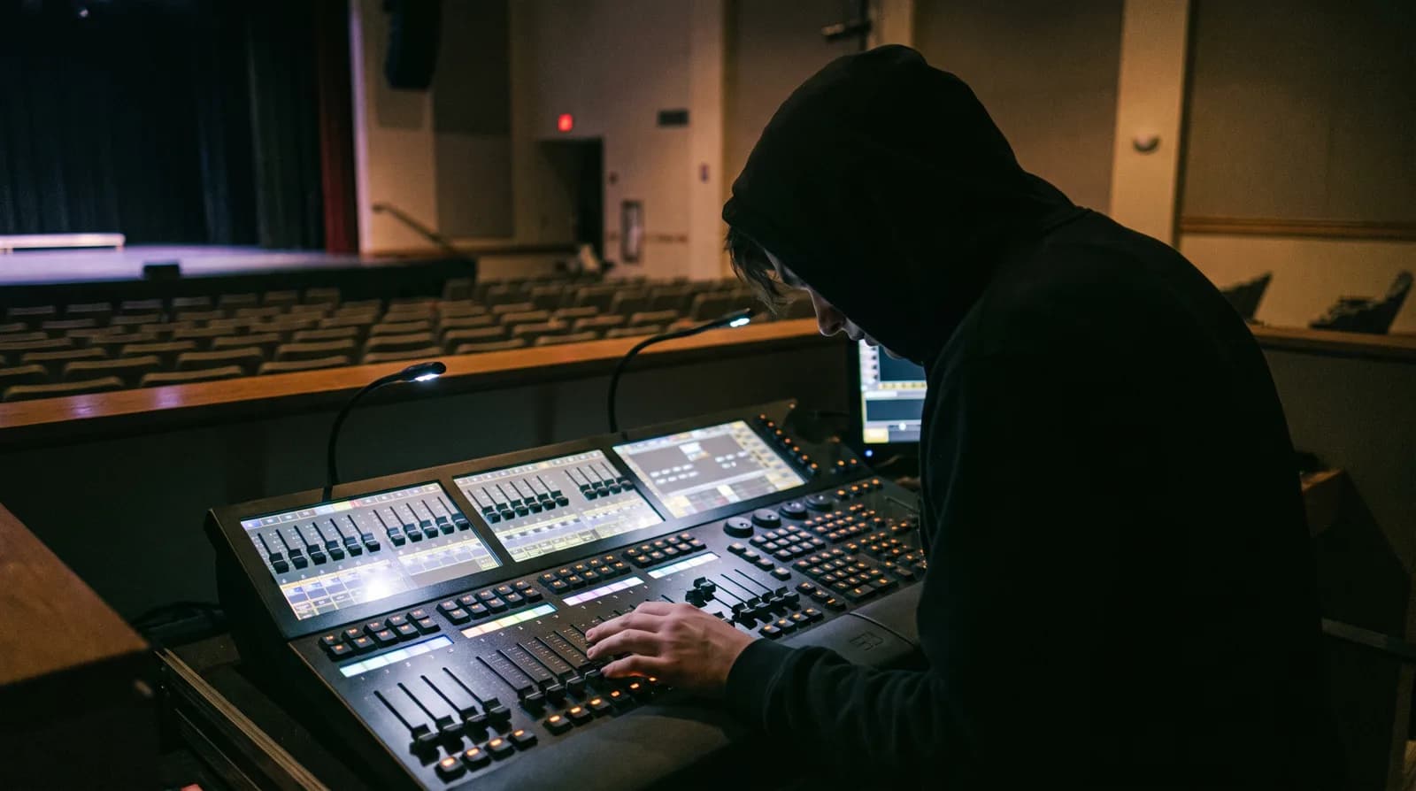 A lighting board operator programming a console at front of house